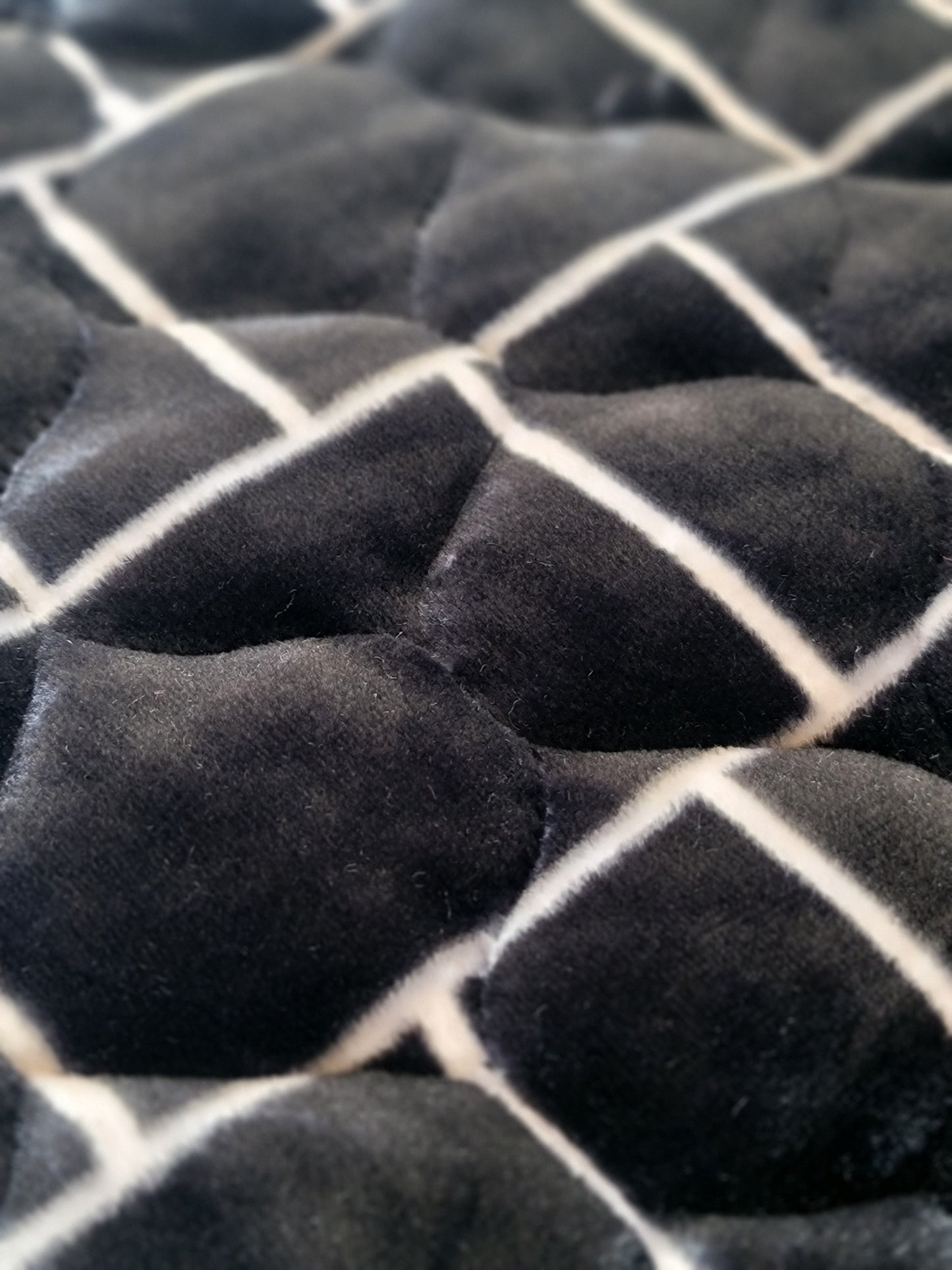 A black jaynamaz - prayer Mate with a motive design, displayed for daily Muslim prayers.